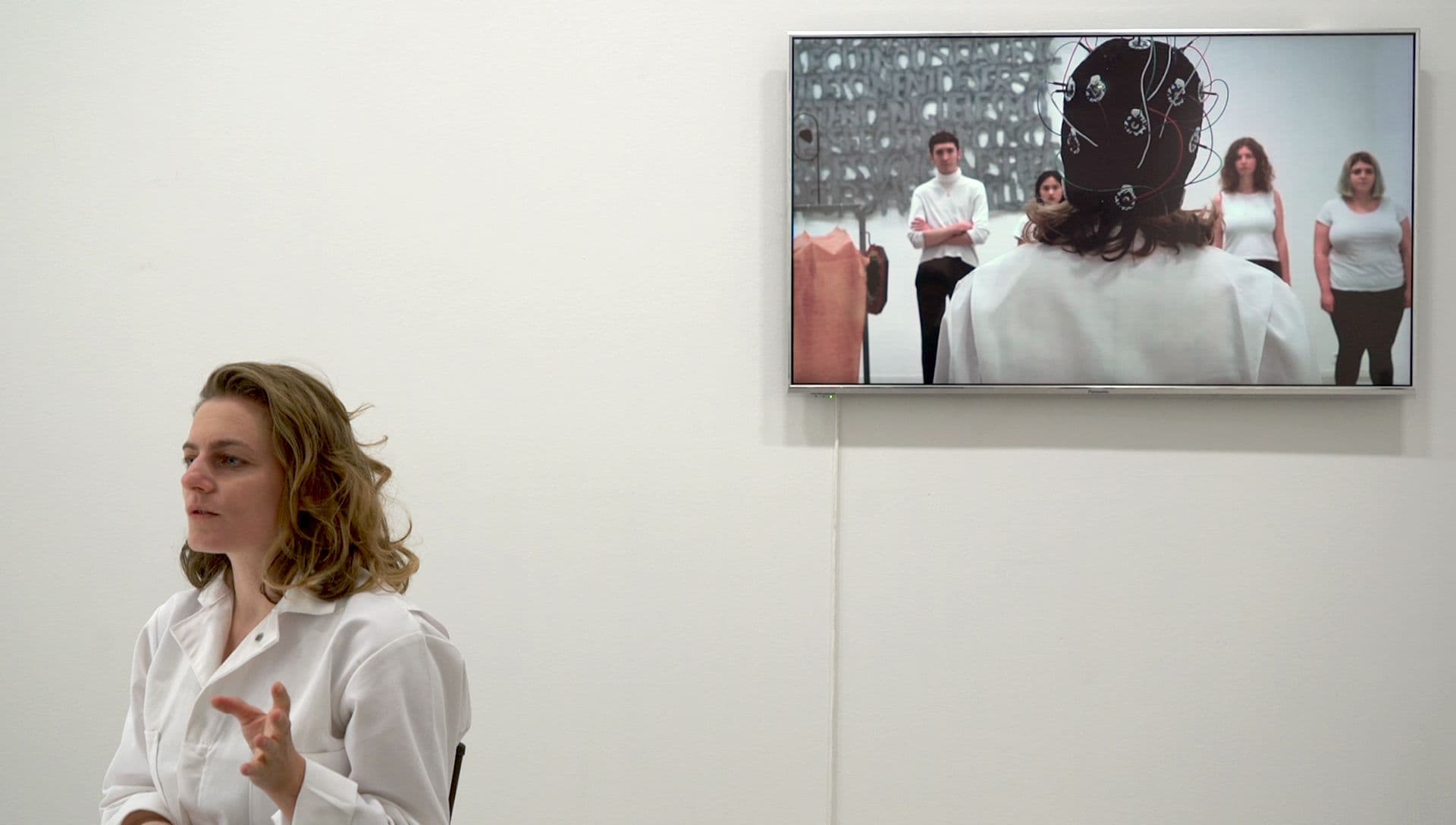 Interview with a woman with tv screen behind.