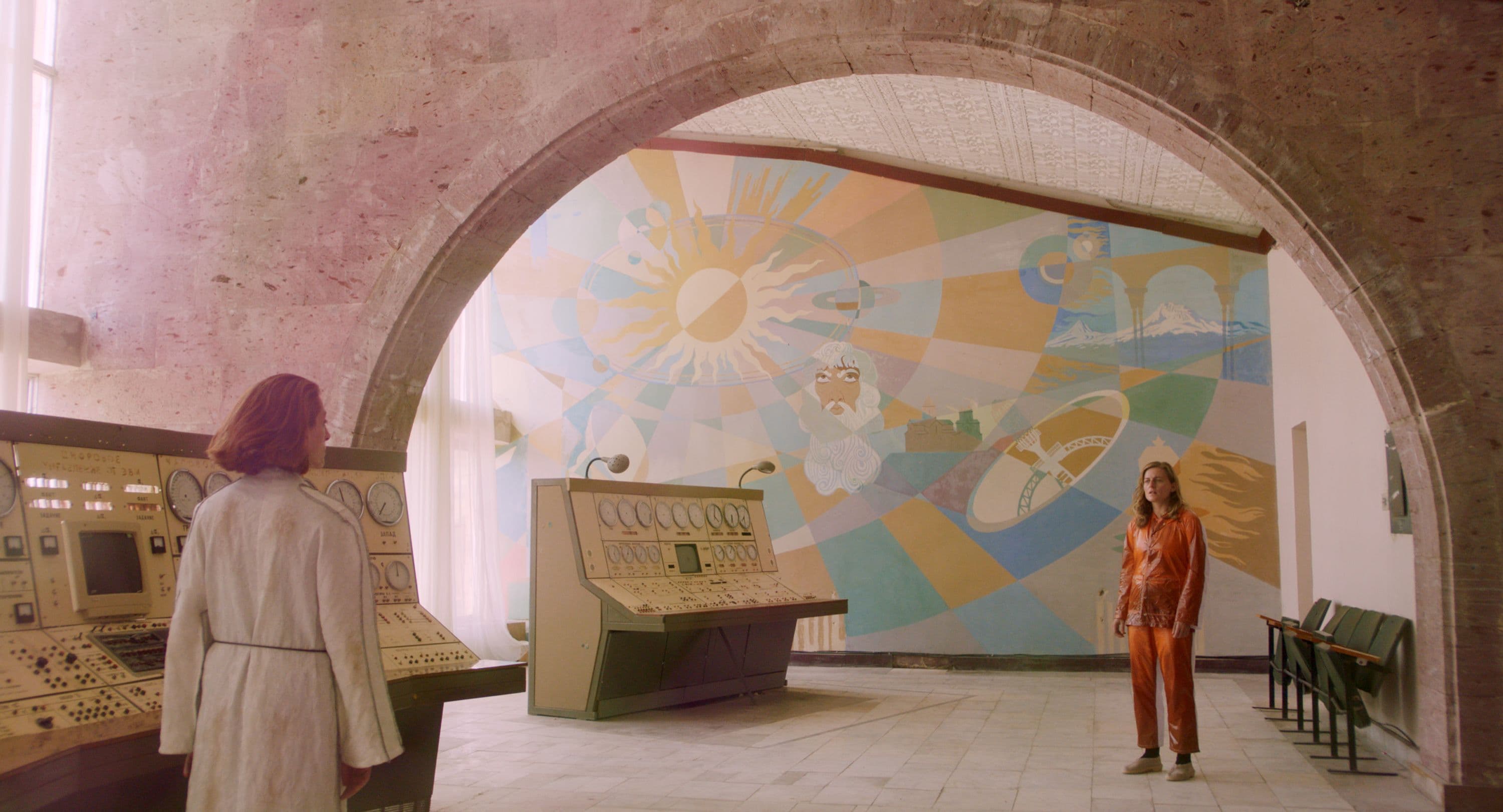 Aliens looking at each other in front of a mural.